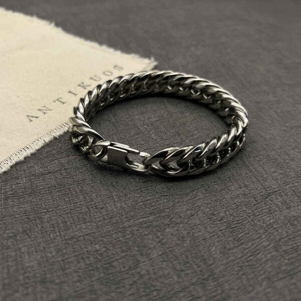 Silver chain bracelet on dark textured surface.