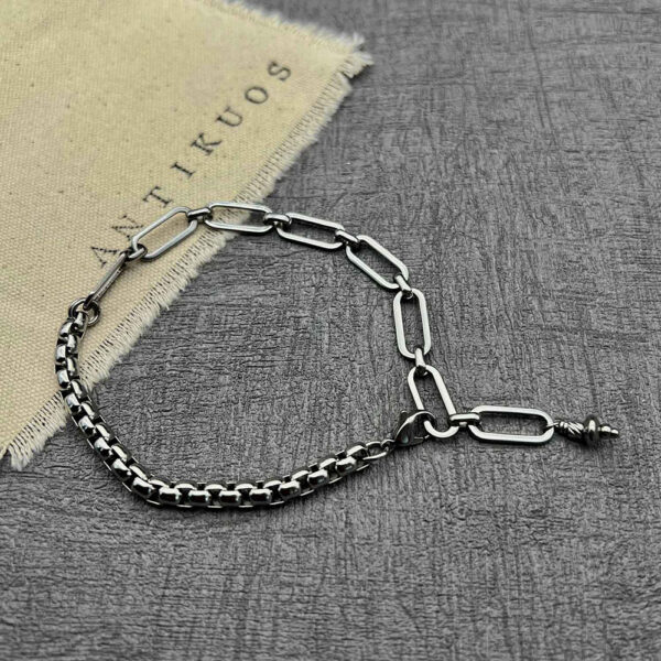 Silver chain bracelet on grey surface.
