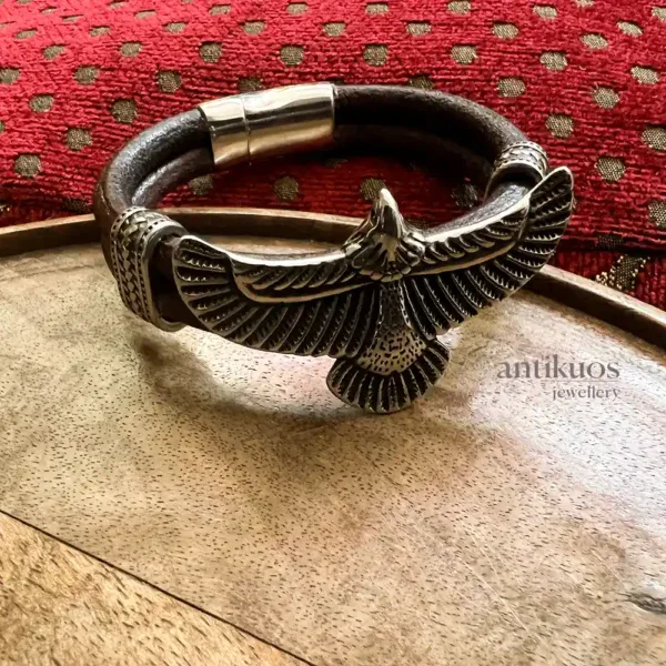 Silver bird bracelet on wooden table.