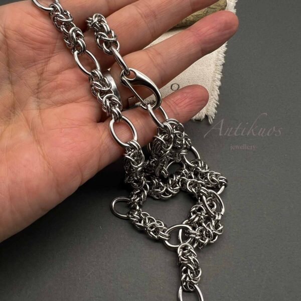Hand holding intricate silver chain jewellery.