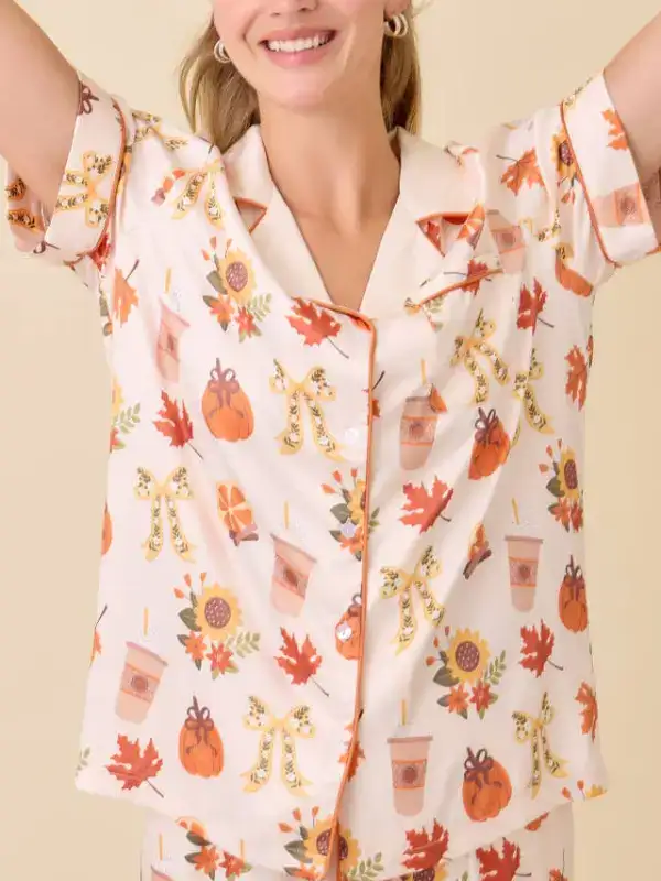 Cream colored short-sleeve pajama set featuring a cozy fall harvest motif including autumn leaves, pumpkin spice lattes, and small pumpkins, soft modal fabric.