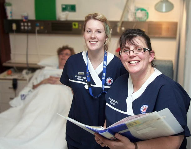 Two nurses standing by a patients bed