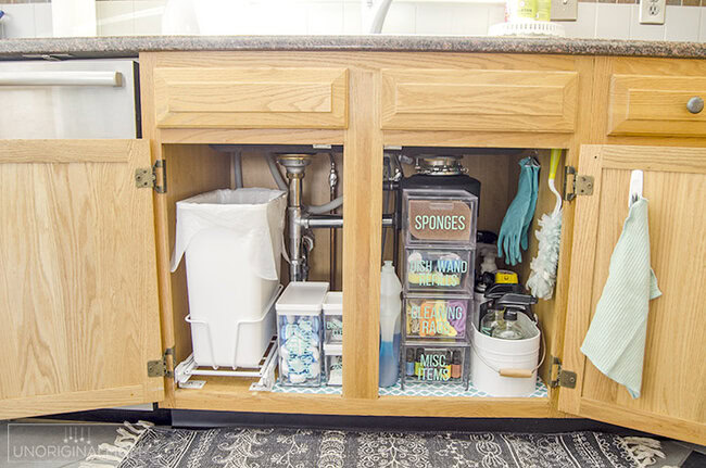 garbage can and cleaning products organized neatly under a kitchen sink