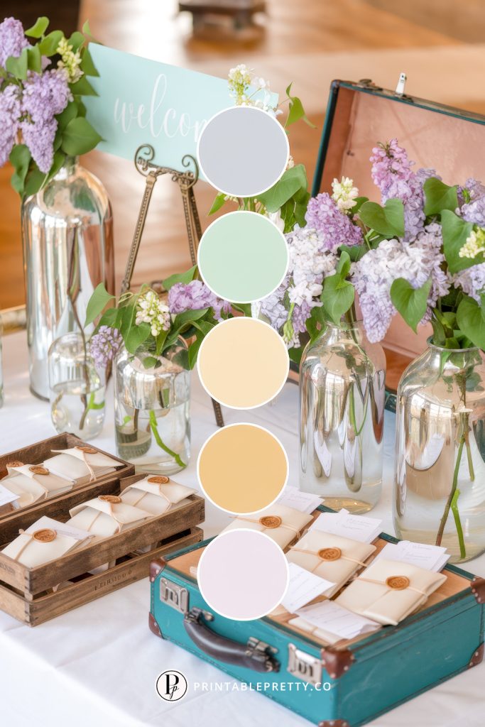 54 Spring Wedding Color Palettes 49 Spring Wedding Color Palette With Dusty Lilac, Mint Green, Pale Yellow, Golden Cream, And Blush Ivory Overlaid On Image Of Wedding Welcome Table With Lilac Blooms, Wax-Sealed Notes, Glass Vases, And Vintage Suitcase