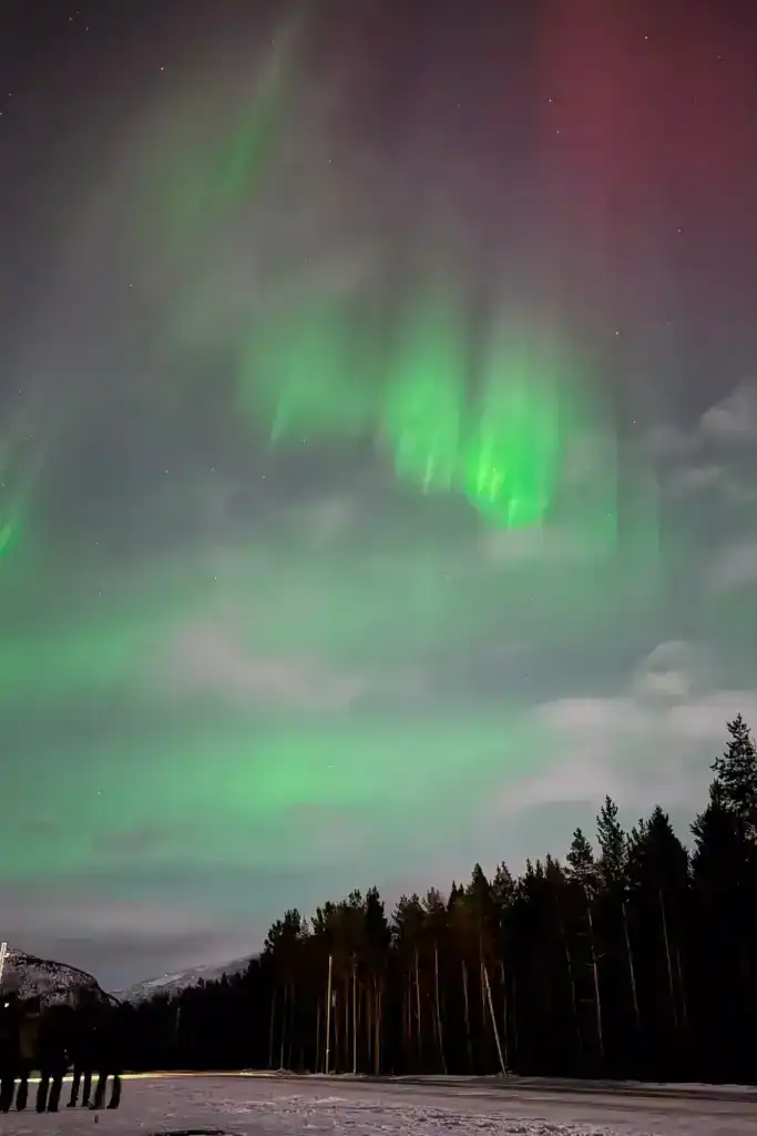 The northern lights in the sky with a hint of pink and red as well as the green