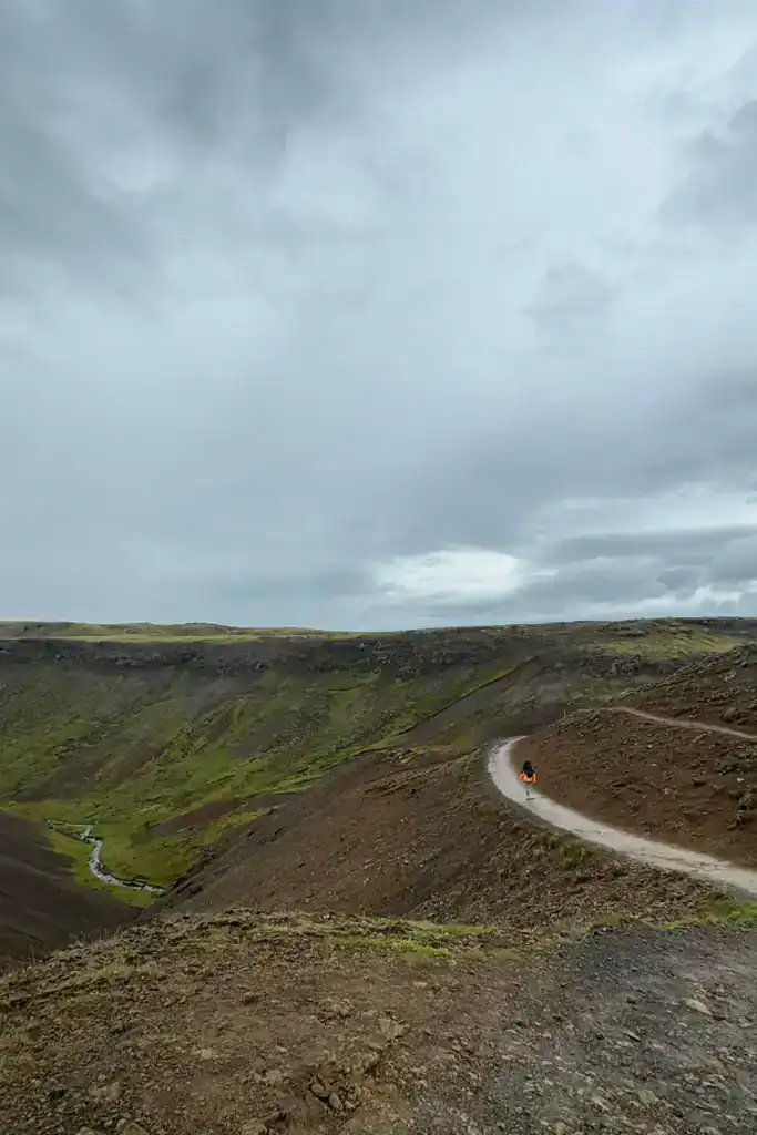 Winding dirt path along a volcanic landscape under cloudy sky in Iceland.