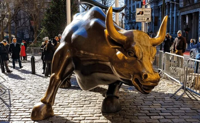 Bronzestatue des Charging Bull an der Wall Street mit Touristen im Hintergrund.