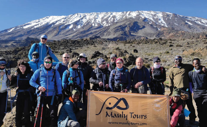 Marangu Route: Climbers celebrating at the highest point in Africa on Mount Kilimanjaro.