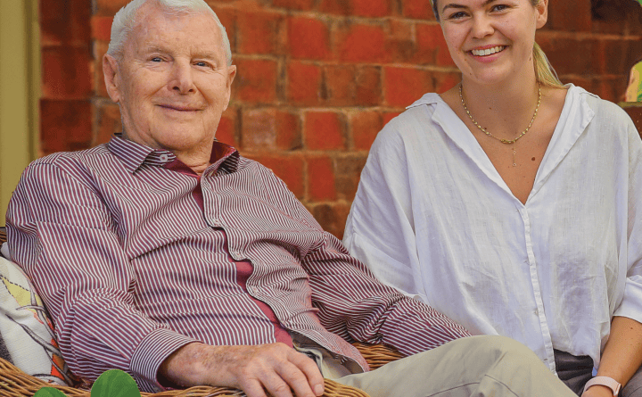 Man and woman sitting on chairs, looking at the camera