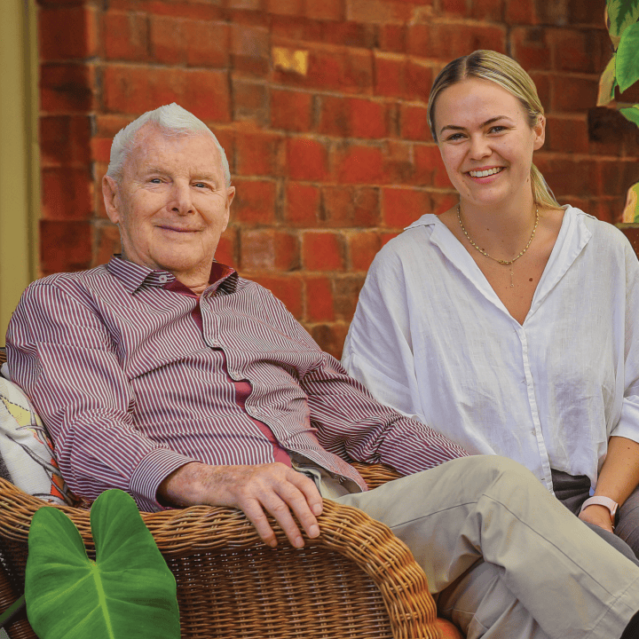 Man and woman sitting on chairs, looking at the camera