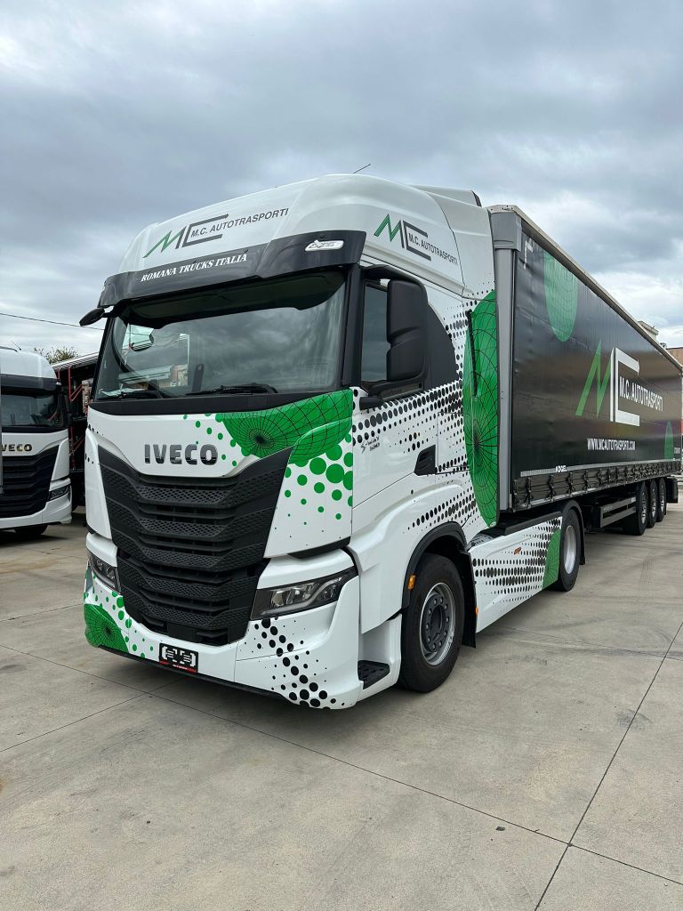 Camion Iveco dell'azienda M.C. AUTOTRASPORTI, con design distintivo e logo visibile, parcheggiato in un'area all'aperto.