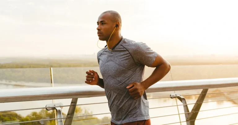 Man running across a bridge at sunrise