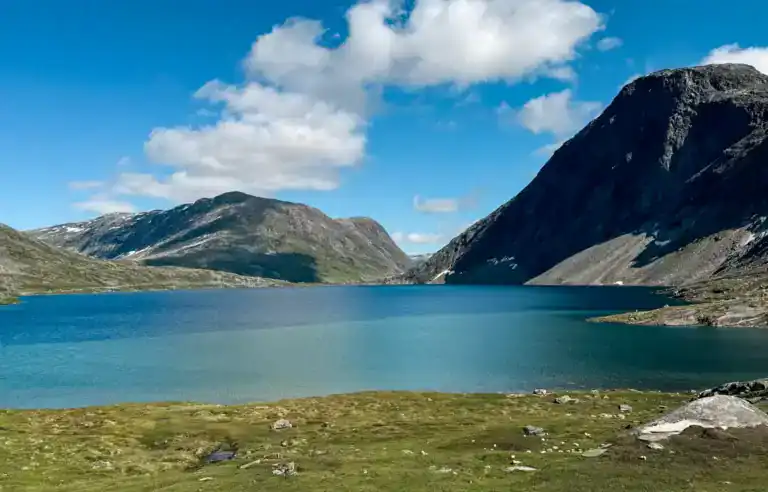 Scenic view of a mountain lake surrounded by rugged hills and partly cloudy sky.