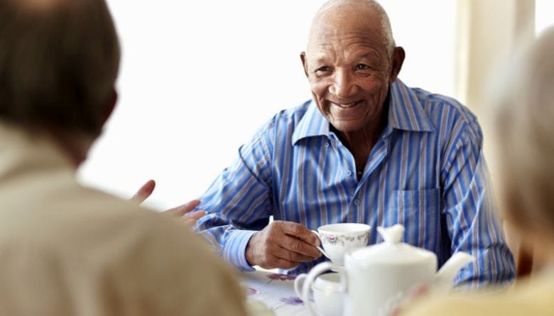 Happy senior man having breakfast with friends