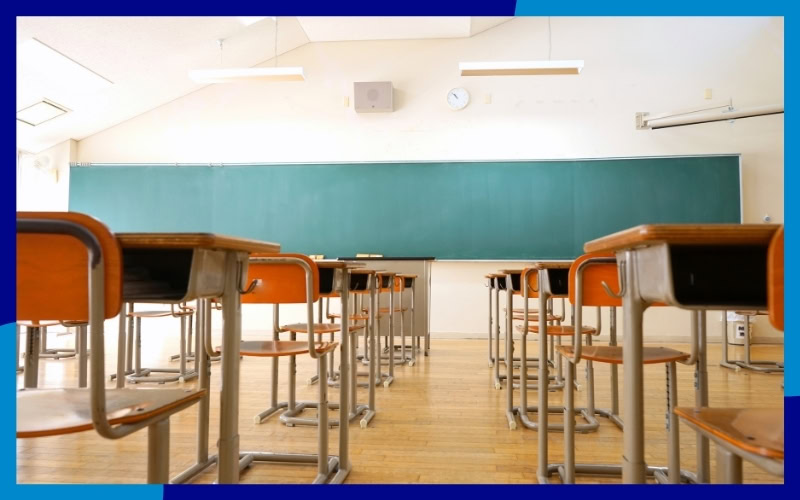 Interno di un aula, con banchi e una lavagna appesa alla parete