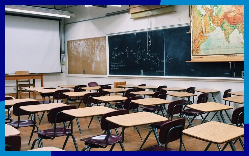 Interno di un aula con banchi, sedie e una lavagna
