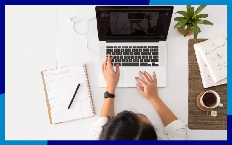 Ragazza al computer, sulla scrivania ci sono anche un'agenda, una penna e una tazza di the