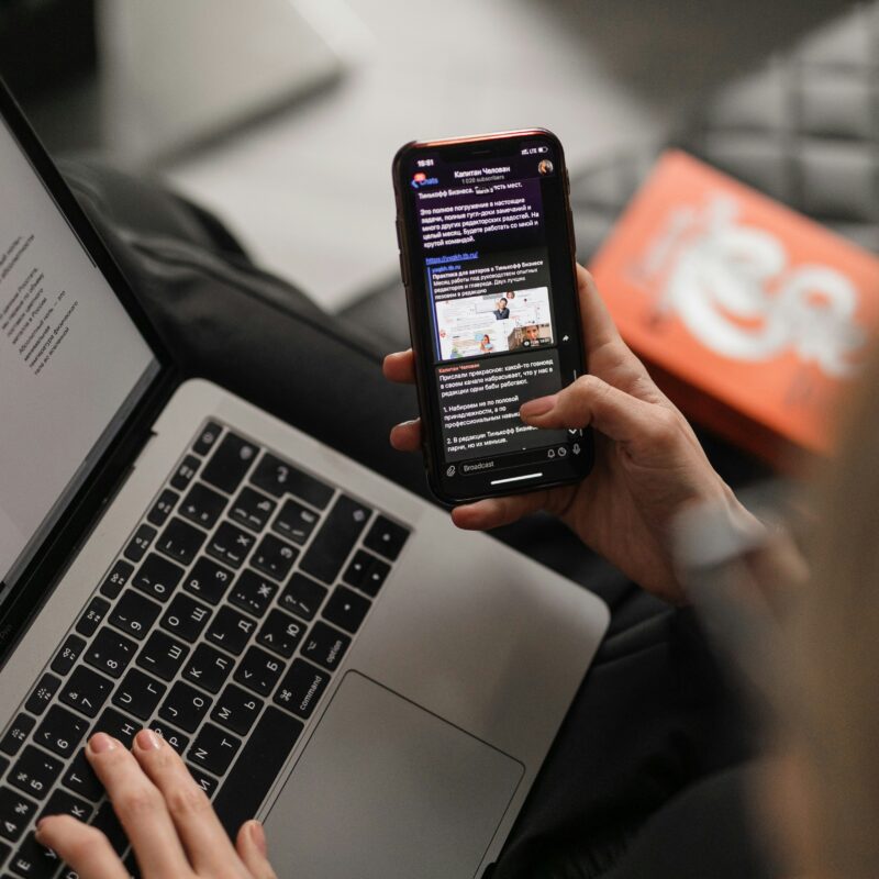 a woman multitasking work phone and laptop.