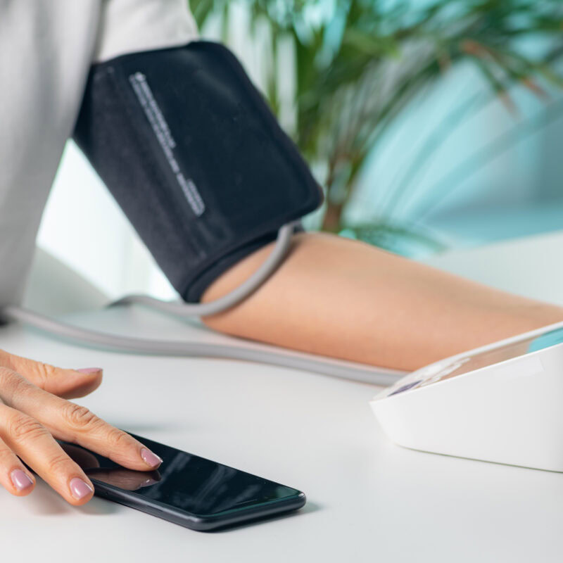 How to Market Medical Devices to Consumers article banner featuring a woman using an at-home blood pressure medical device