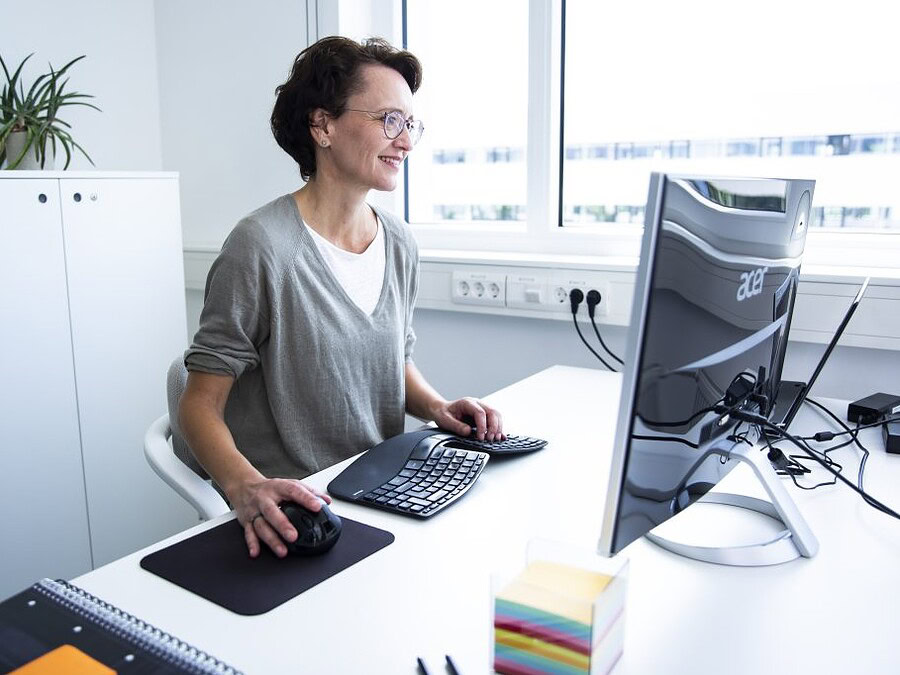 Blogbeiträge schreiben: Eva Dragosits sitzt am Schreibtisch und schaut auf den Screen