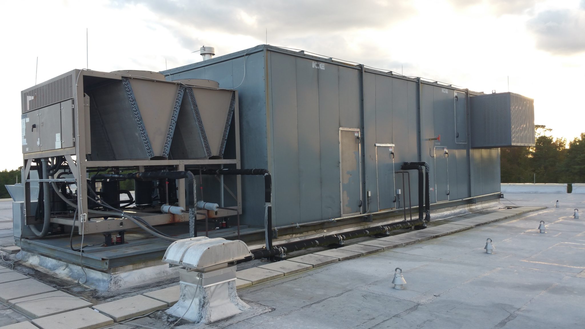Large industrial HVAC unit on a rooftop with connected piping.