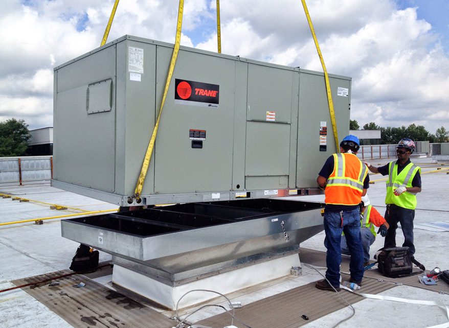 Workers installing a large rooftop HVAC unit.