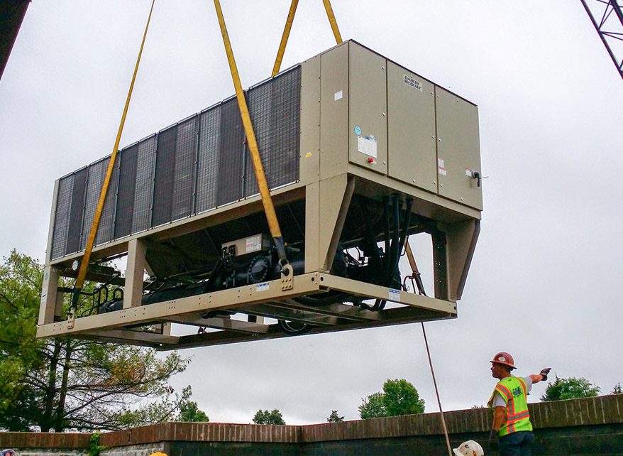 A large industrial unit being lifted by cranes at a construction site.