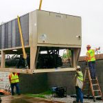 Thumbnail of http://Workers%20install%20a%20large%20industrial%20unit%20using%20cranes%20and%20ladders.