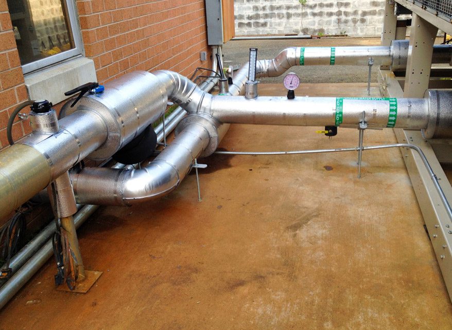 Industrial pipes and valves installed on a concrete floor.
