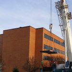 Thumbnail of http://Crane%20lifting%20a%20heavy%20object%20beside%20a%20brick%20building.