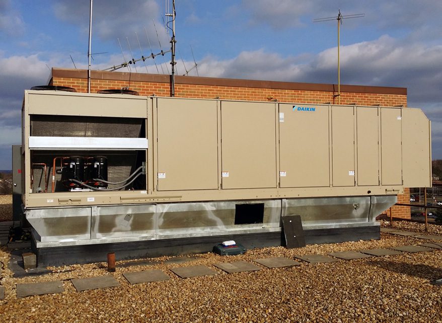 Large beige industrial HVAC units on a rooftop under a partly cloudy sky.
