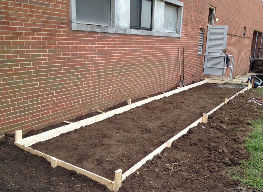Freshly prepared rectangular garden bed with wooden frame.