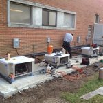 Thumbnail of http://Technician%20working%20on%20HVAC%20units%20outside%20a%20brick%20building.