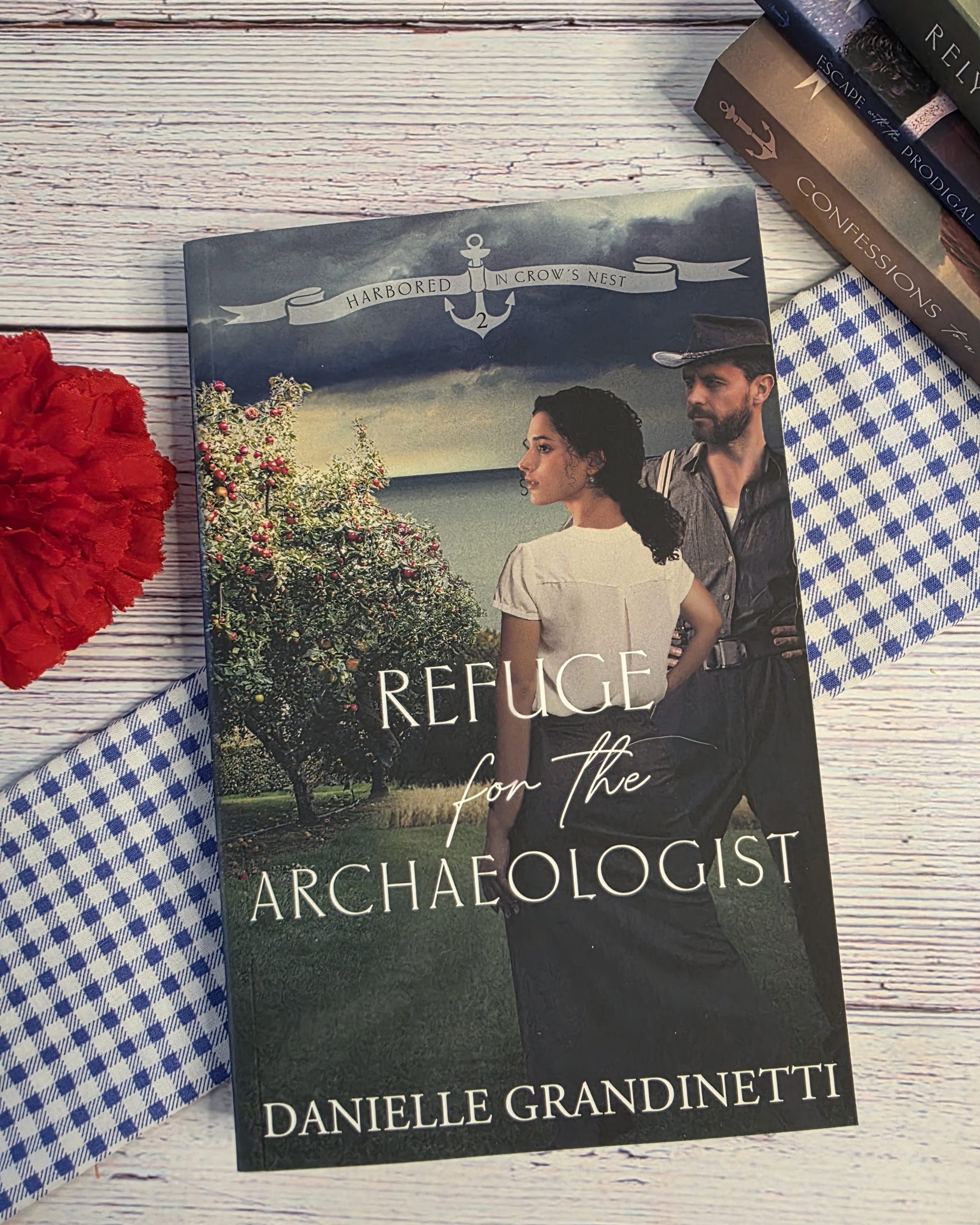 Book cover titled 'Refuge for the Archaeologist' by Danielle Grandinetti, showing a man and woman outdoors with an anchor motif and ribbon banner.