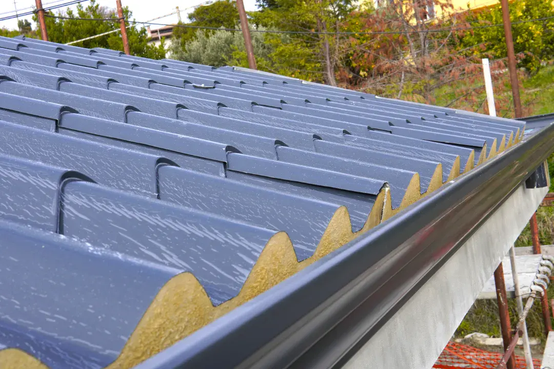 Solid conservatory roof installation showing insulation boards and blue tile effect cladding with anthracite gutter.
