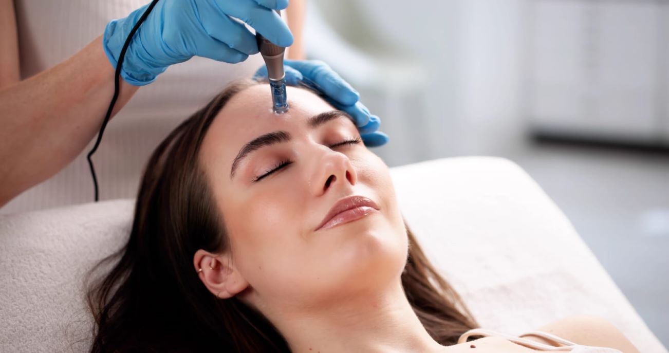 Close-up of a woman's forehead during a microneedling treatment with a dermapen device