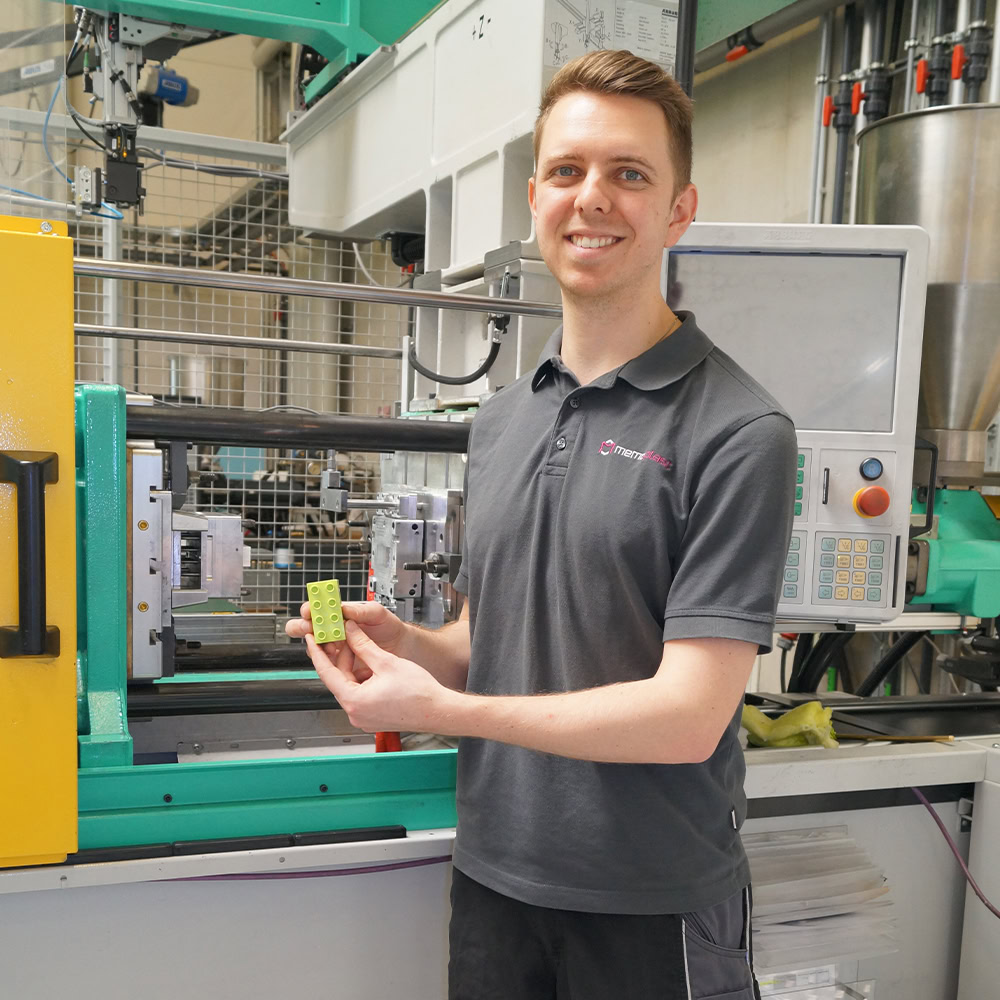 Auszubildender Verfahrensmechaniker bedient moderne Spritzgussmaschine