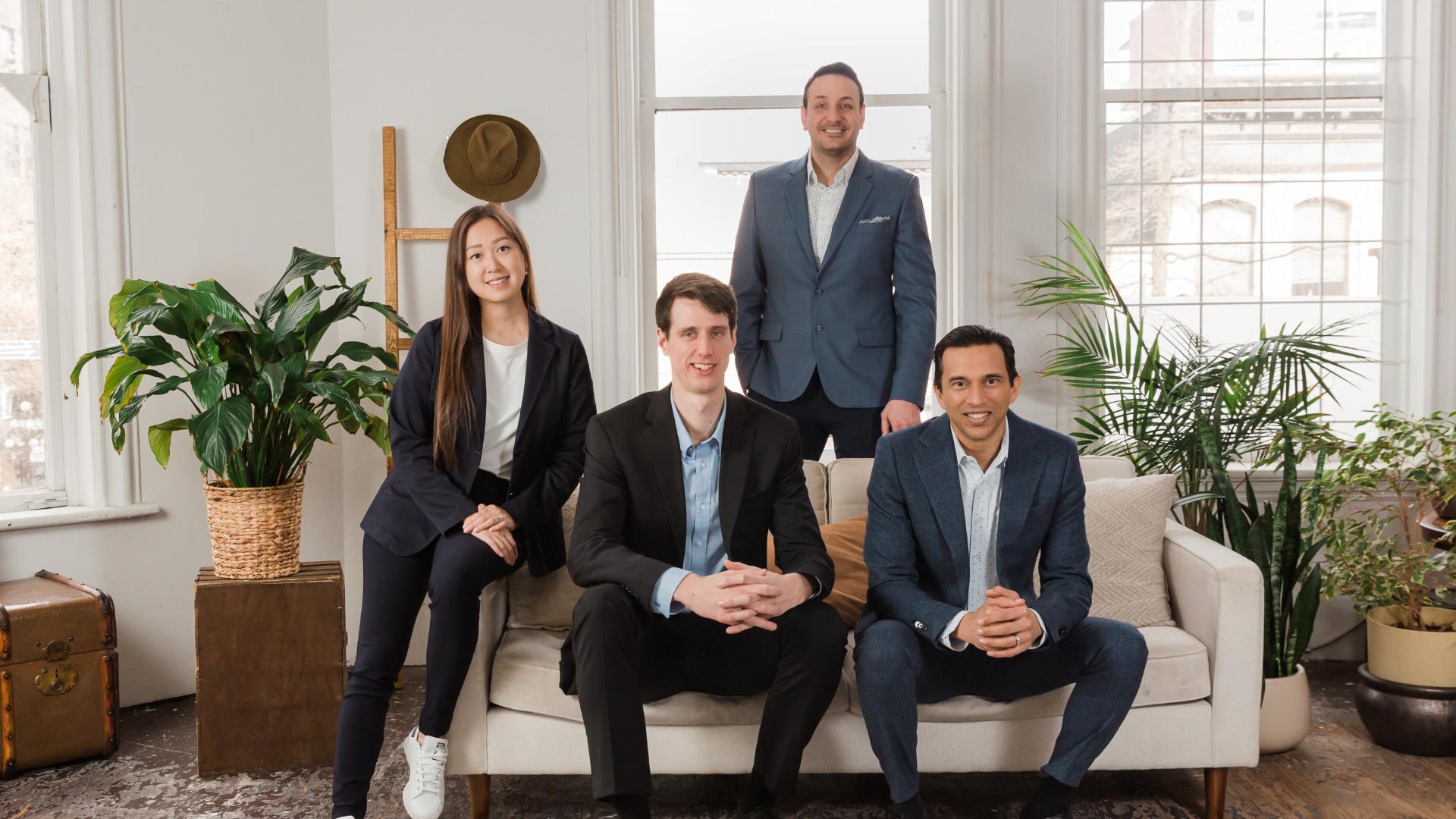 The Safe Pacific Financial team sitting on a white sofa in a stylish room. Probably discussing how they set up the Infinite Banking Concept for their clients across Canada.