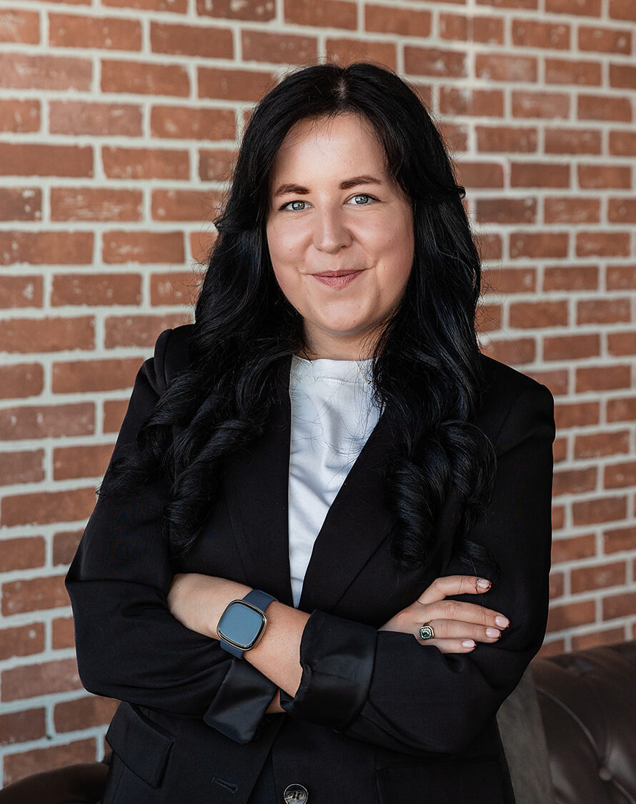 Megan Darling, Safe Pacific Financial wealth advisor, stands smiling in front of a brick wall, expert in infinite banking and bespoke Canadian life insurance.