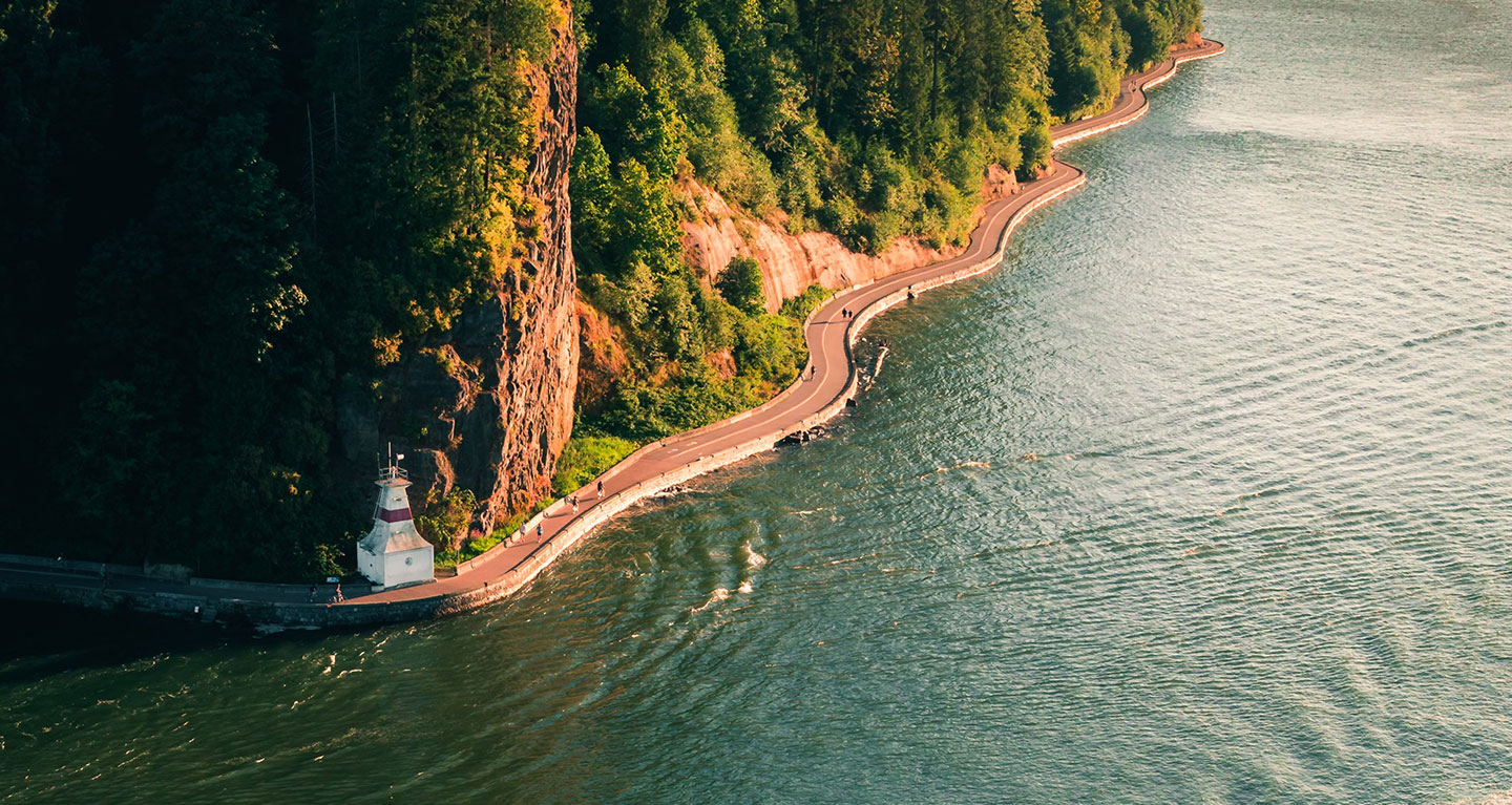 A winding road by a cliff and water, with a lighthouse—symbolizing Safe Pacific Financial’s tailored wealth management guidance.