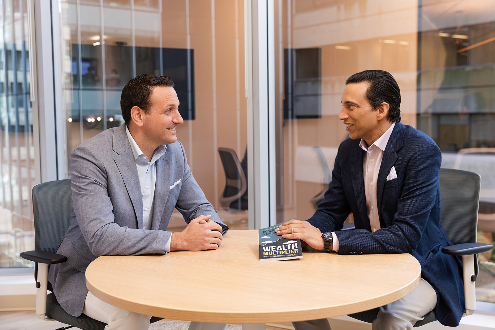 Two men in business attire at Safe Pacific Financial discuss infinite banking, bespoke Canadian life insurance, and wealth management.