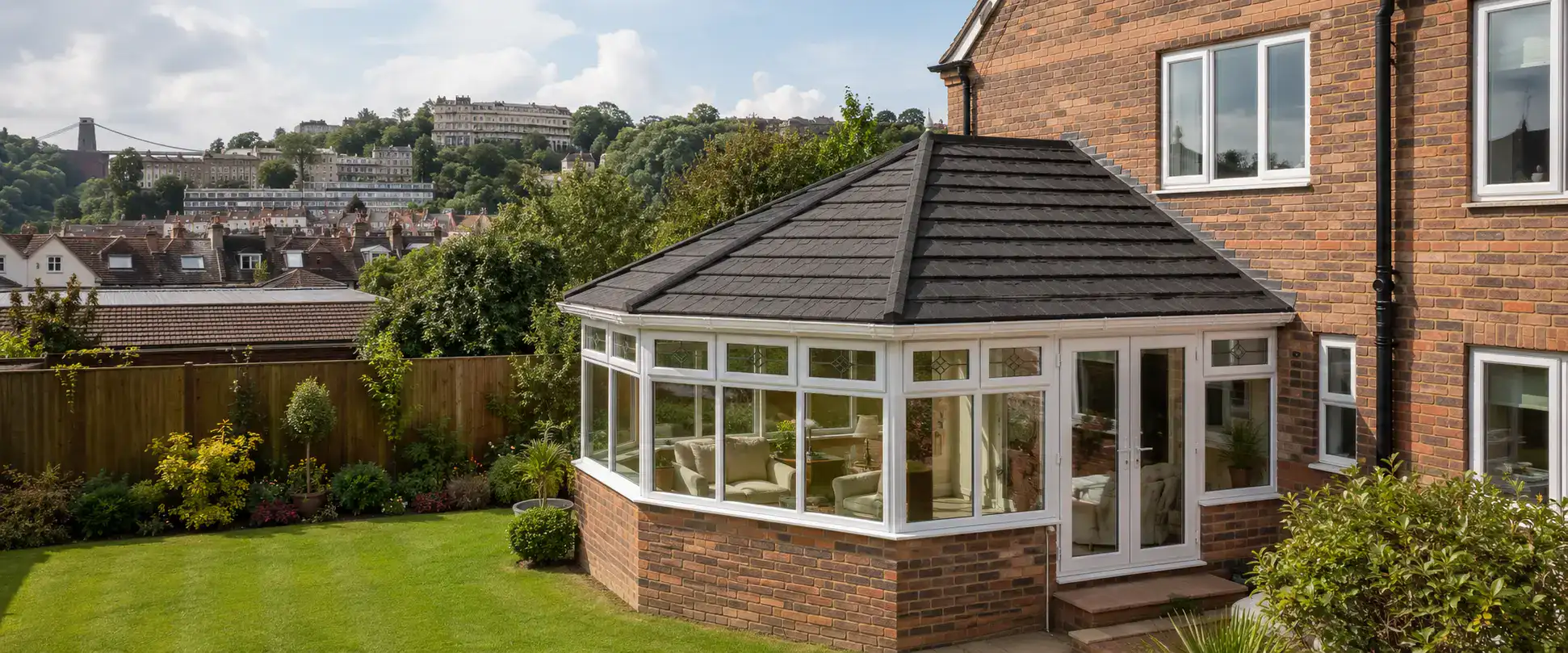 A modern conservatory roof replacement in Bristol featuring a dark grey tiled solid roof on a brick conservatory, demonstrating a local energy-efficient home upgrade.