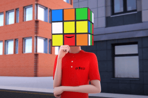 A person wearing a red shirt stands on a city street with a Rubiks cube for a head, featuring a smile on one of the cubes squares.