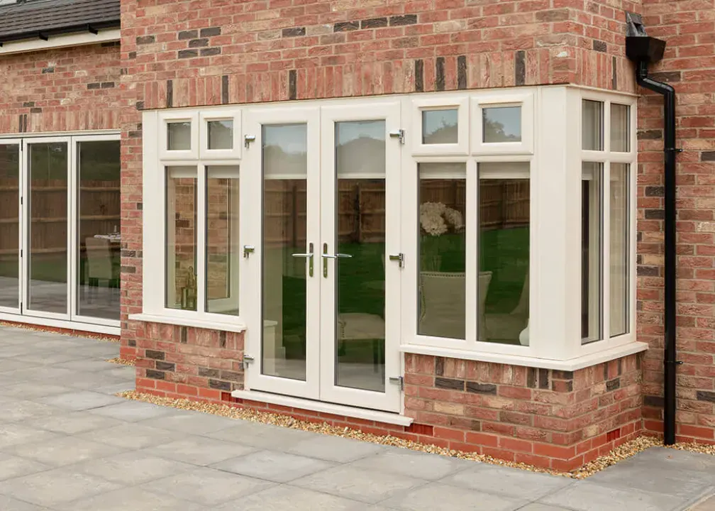 Aluplast cream uPVC French doors with matching bay window installed in a brick house extension