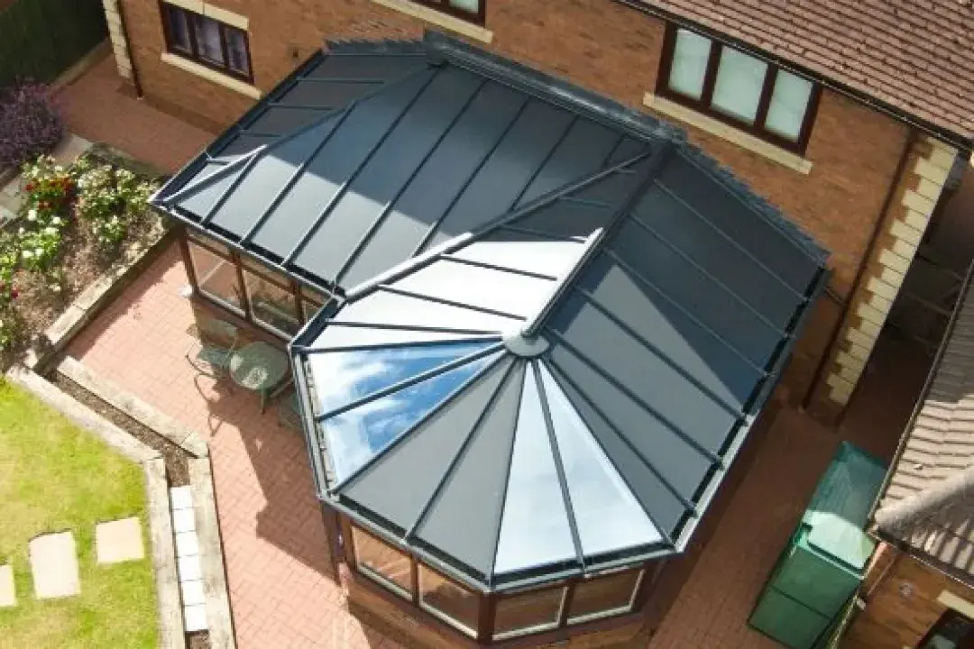 Combination conservatory with a glazed roof, dark frames and brick base viewed from above.