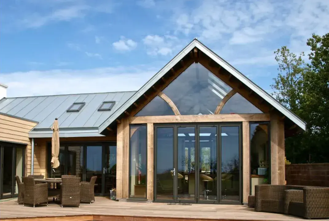 Black aluminium bifold doors beneath a glazed gable on an oak-framed extension