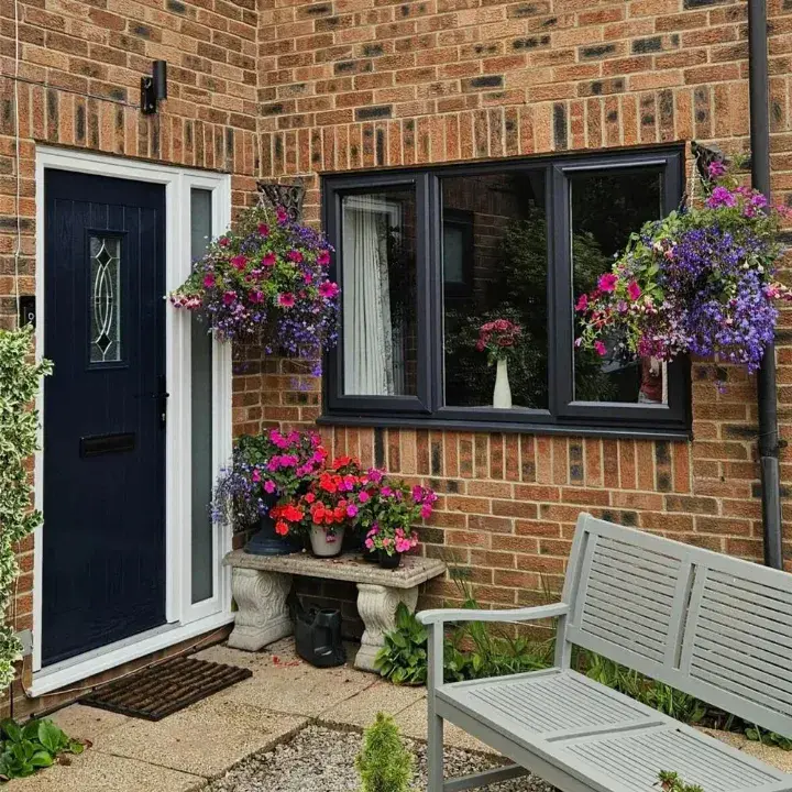 Black composite front door with decorative glazing fitted to a brick home