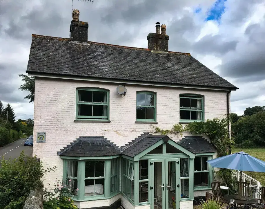 Green uPVC sliding sash windows fitted to a traditional country home