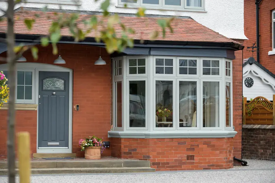 Grey uPVC flush casement bay window with Georgian bars on a red brick home