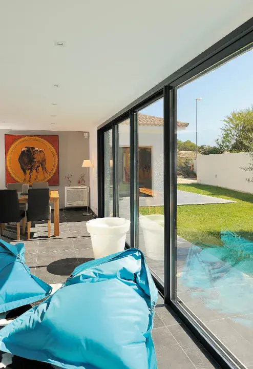 Black aluminium patio sliding doors letting natural light into a bright living space with blue beanbag chairs.